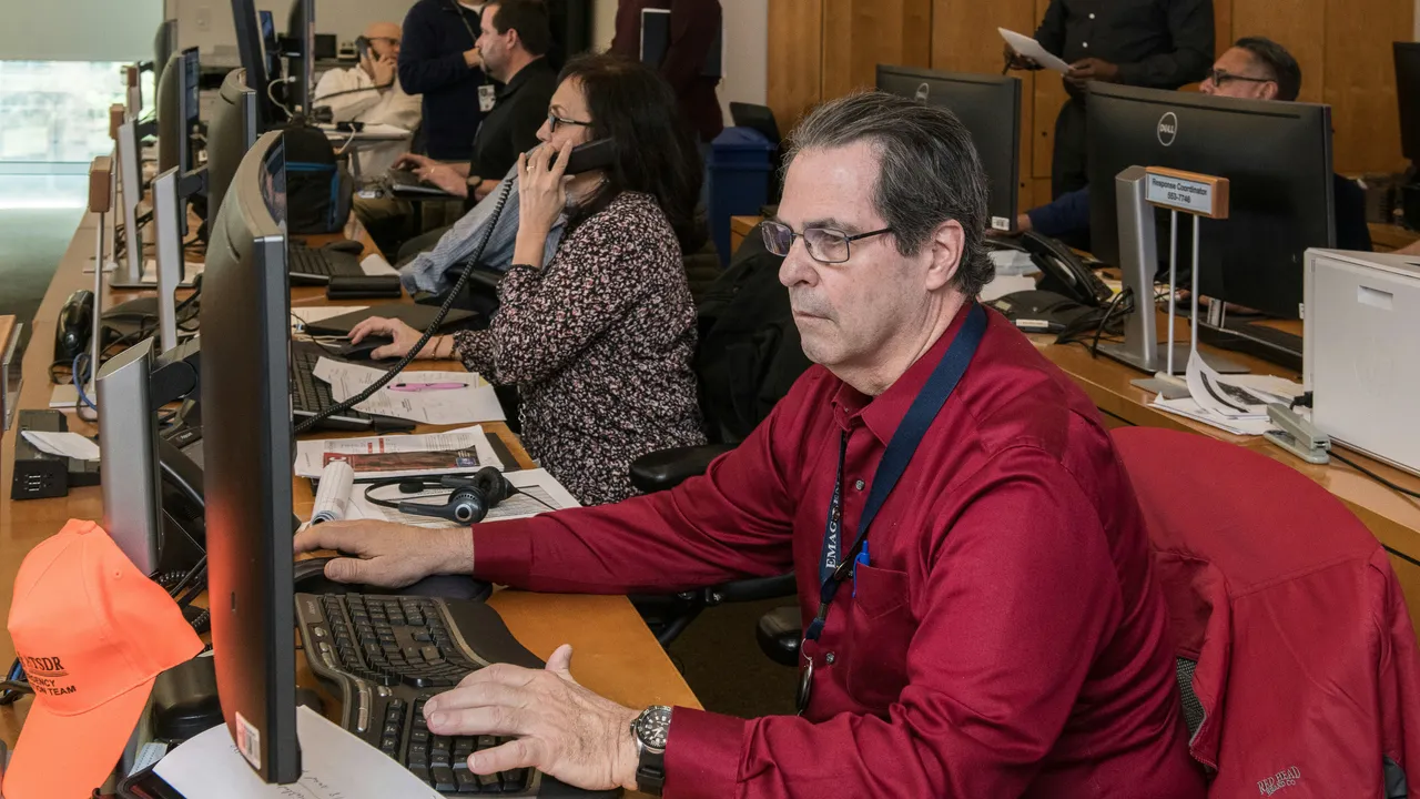 Staff handling calls at workstations in a public-service operations room.
