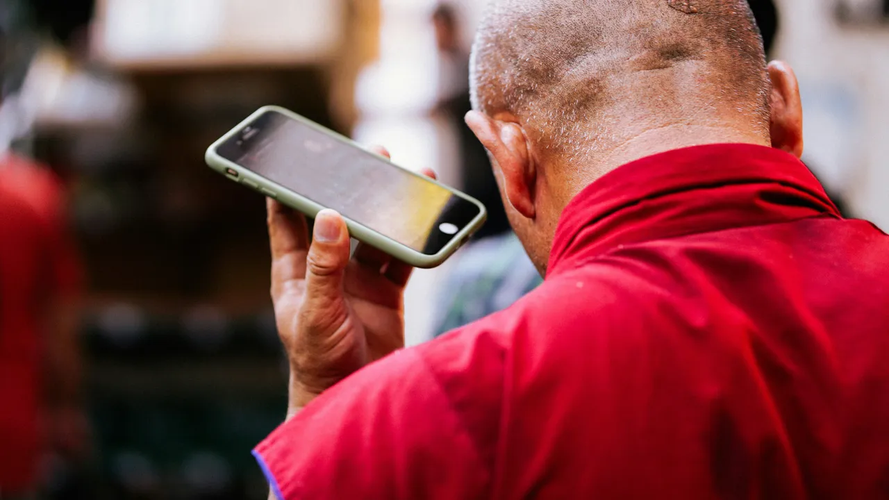 A worker in a red uniform taking a call on a phone in a workshop.