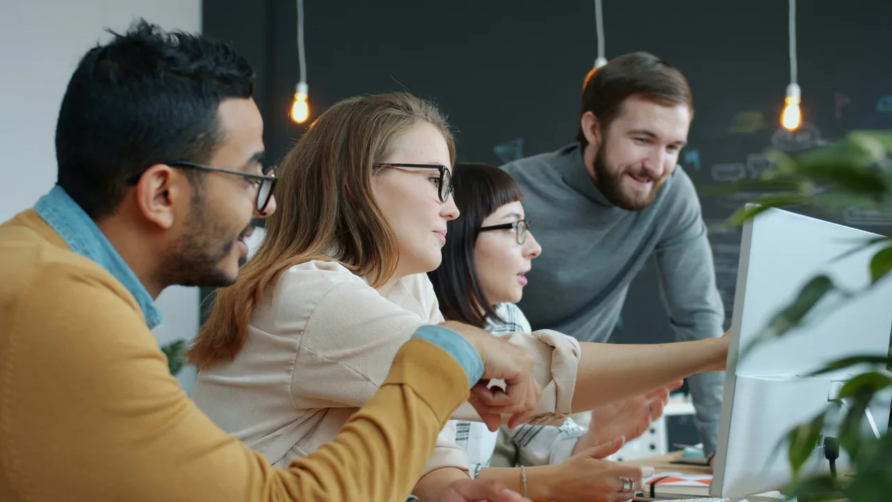 A small startup team gathered around a screen in a coworking space.